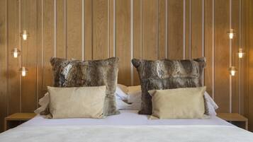 Una cama con dos almohadas grandes y con textura, y un cabecero de madera con líneas verticales.