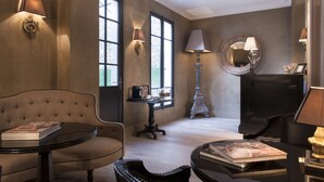 A room with a sofa, a table with a book, a lamp, and a mirror on the wall. - Hôtel Villa Glamour (Paris)