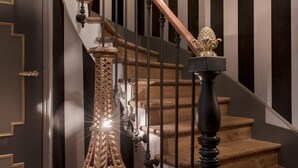 A grand staircase with a wooden handrail, a decorative balustrade, and a wall-mounted light fixture. - Hôtel Villa Glamour (Paris)