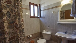 A bathroom with a toilet, sink, and a window. - Angela Apartments (Samos)