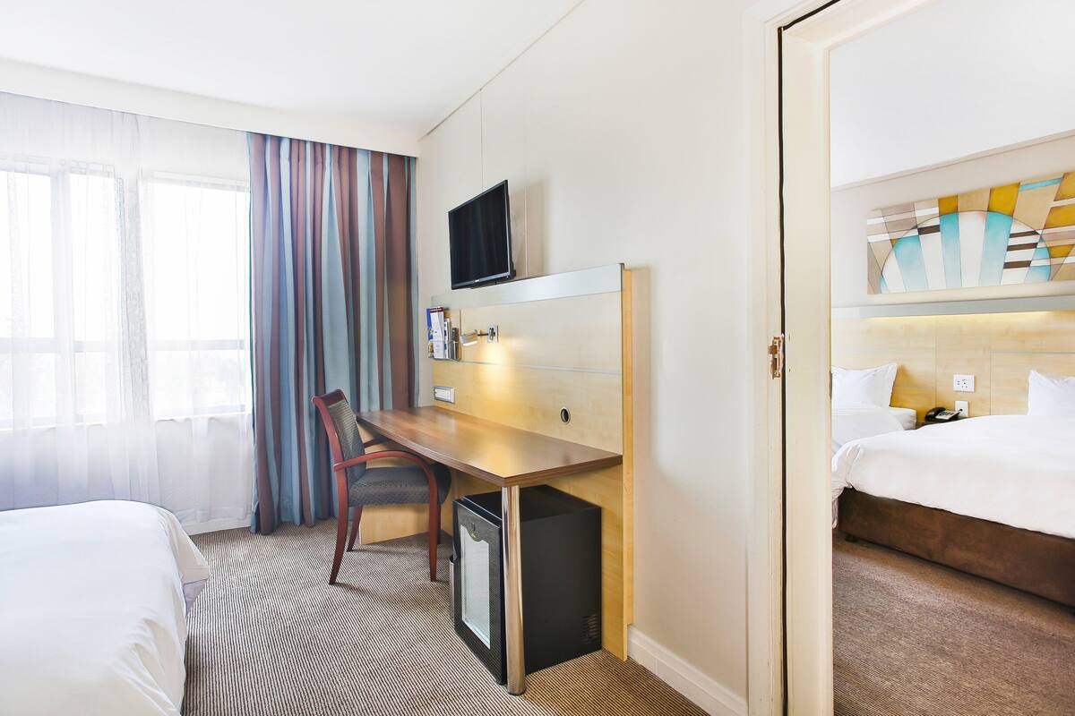 A hotel room with a bed, a desk, a television, and a minibar.