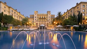 Ein großes Hotel mit einem zentralen Pool, mehreren Lounges und einem beeindruckenden Eingang.
