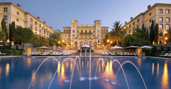 A large hotel with a central pool, multiple lounge areas, and a grand entrance.