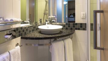 A modern bathroom with a round sink, a glass shower enclosure, and a mirror above the sink.