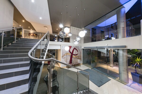 Un interno moderno con una scala, ringhiere in vetro e lampade dal design contemporaneo.