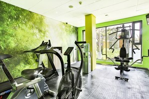 A gym with exercise equipment, a water dispenser, and a large window with a view of greenery. - Holiday Inn Express Sandton Woodmead by IHG (Sandton)