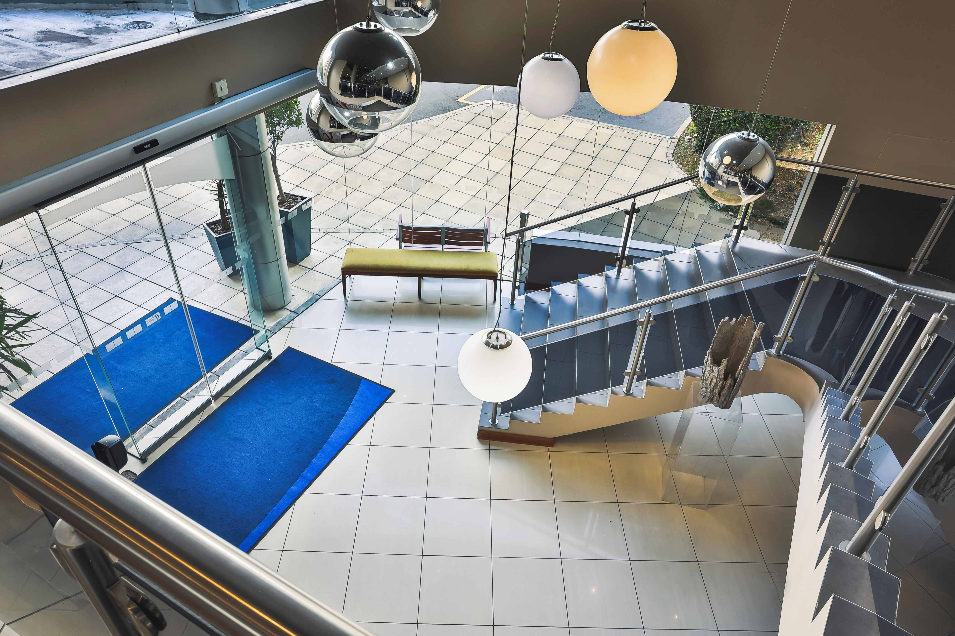 Ein moderner Innenraum mit einem blauen Teppichbereich, einer Bank und einer Treppe mit Metallgeländern.