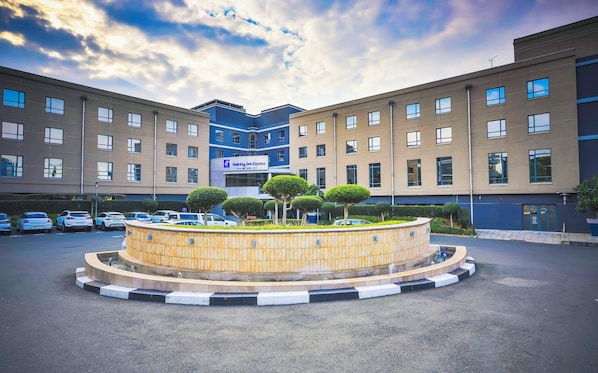 A hotel with a central courtyard featuring a circular water feature and trimmed hedges. - Holiday Inn Express Sandton Woodmead by IHG (Sandton)