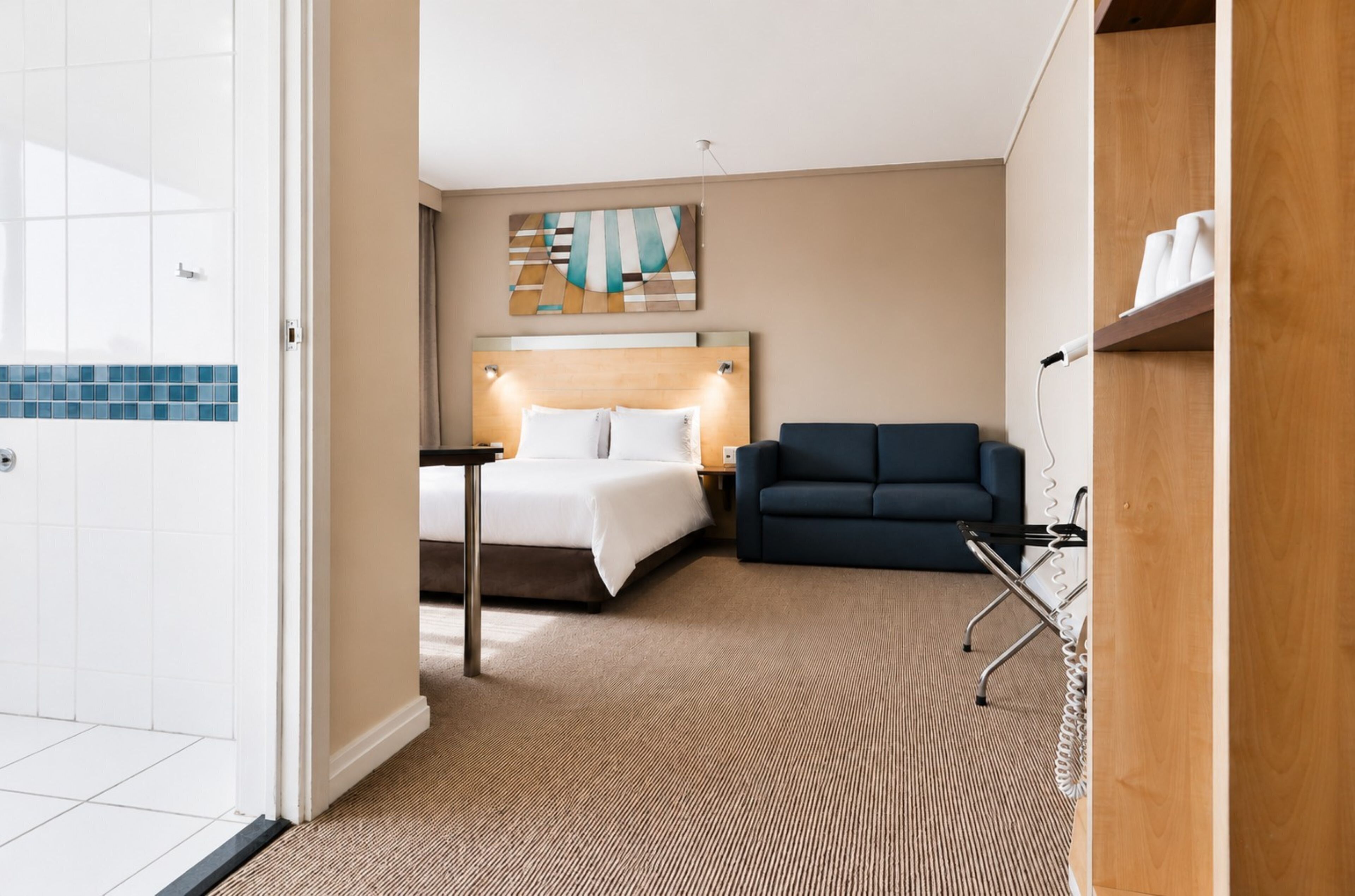 Ein Hotelzimmer mit einem Bett, einem Sofa, einem Schreibtisch und einem Wandbild.
