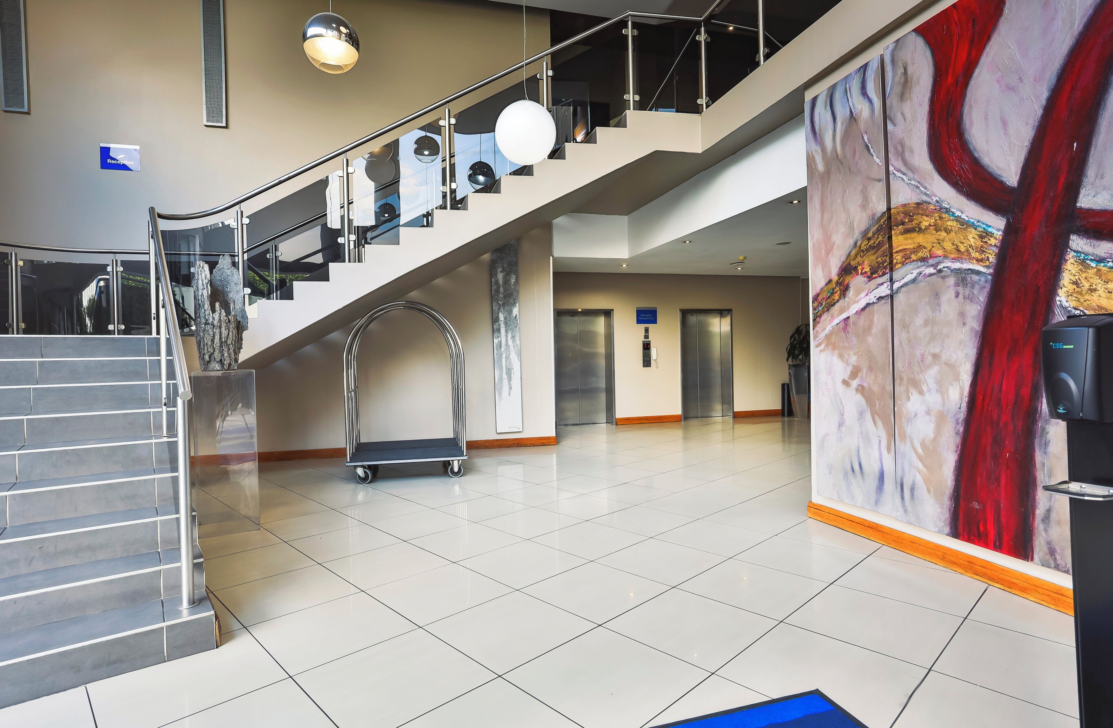 Un vestíbulo moderno con una escalera, ascensores y una recepción.