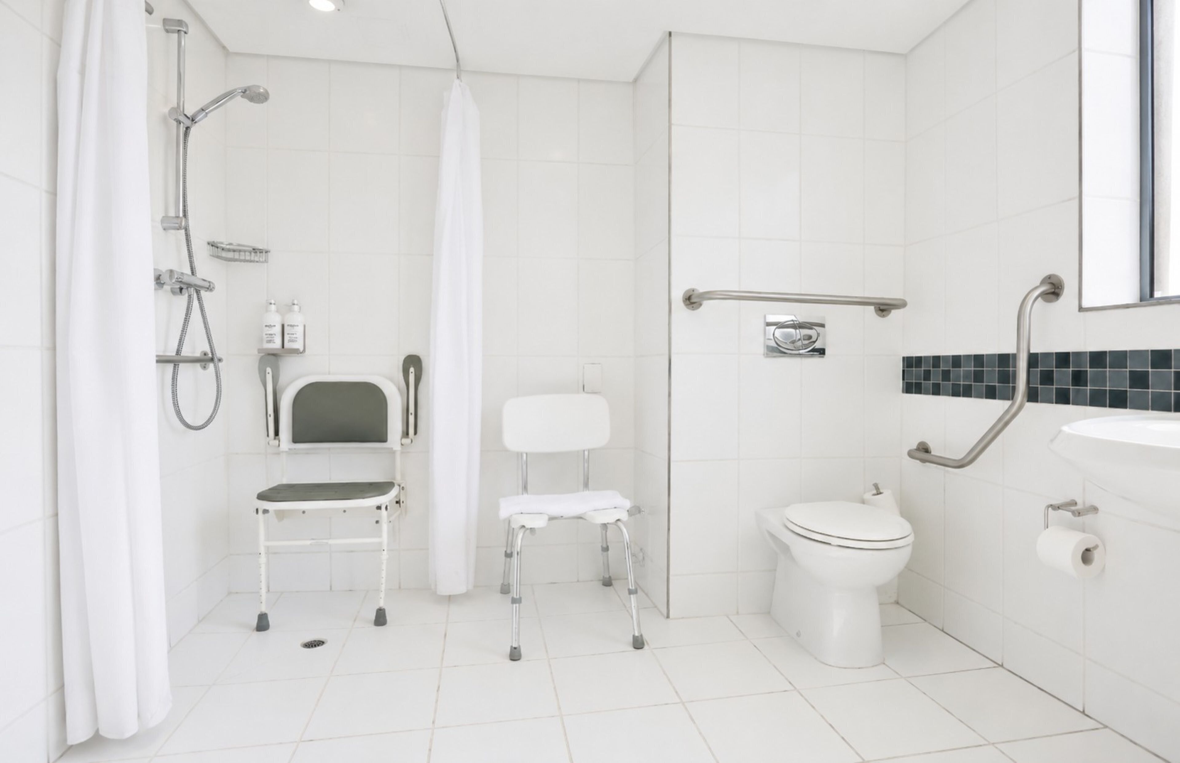 Un baño moderno con ducha, inodoro y una silla accesible para sillas de ruedas.