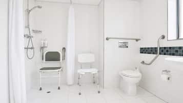 Un baño moderno con ducha, inodoro y una silla accesible para sillas de ruedas.