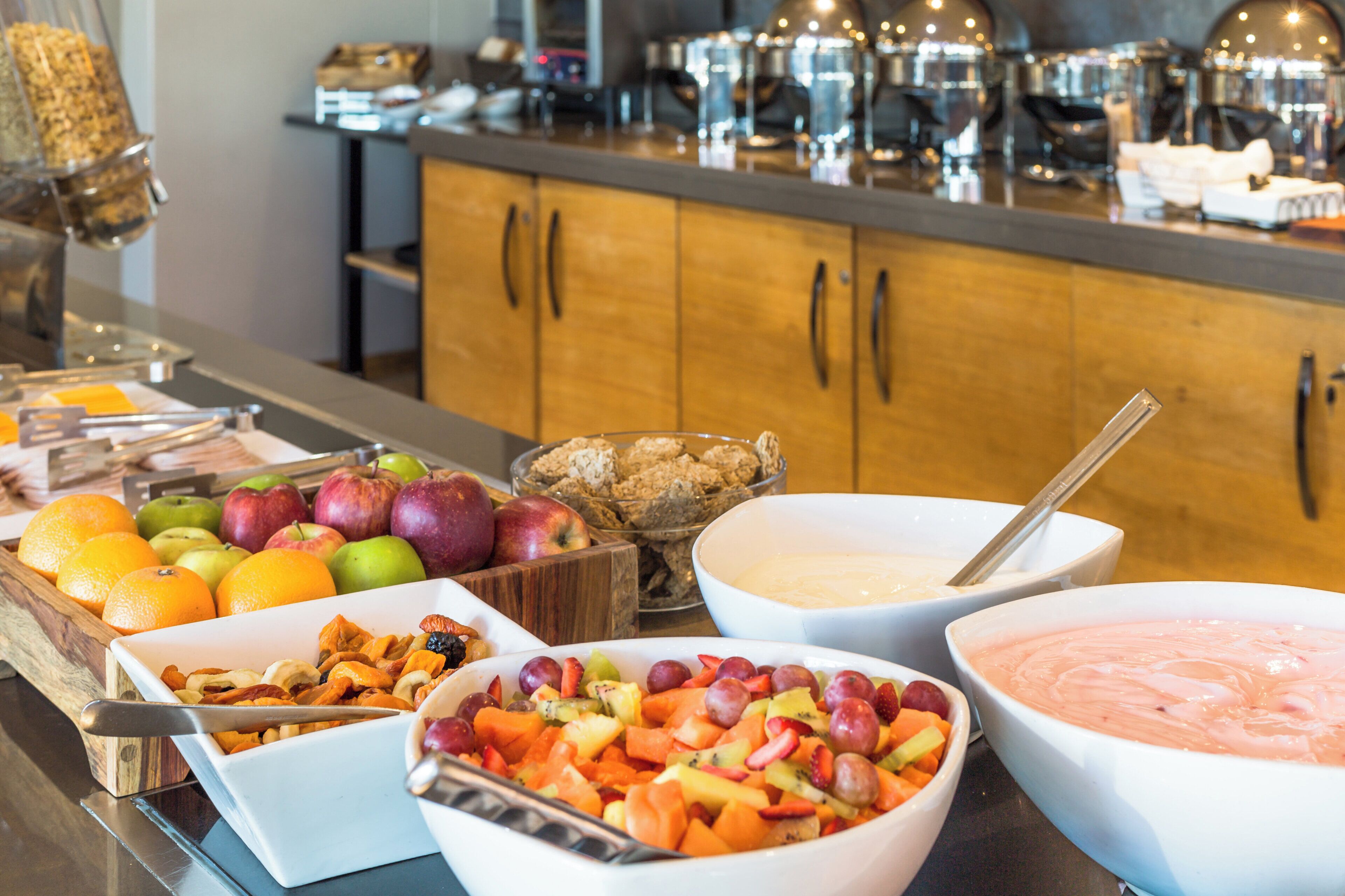 A buffet with various fruits, nuts, and a bowl of dip.
