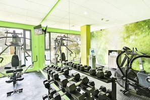 A gym with various exercise equipment, including dumbbells, a treadmill, and weight machines.