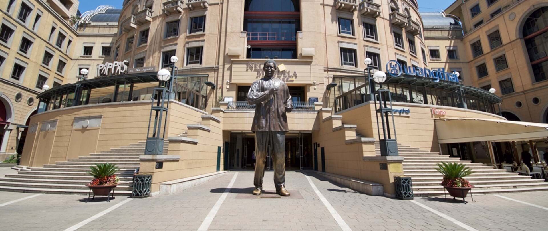 A building with a statue in front, featuring multiple entrances and a staircase leading to the ground level.