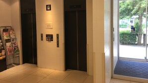 An elevator with a digital display, emergency exit sign, and a door with a handle.