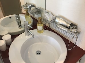 Bagno con due lavandini, asciugacapelli ed erogatore di sapone.