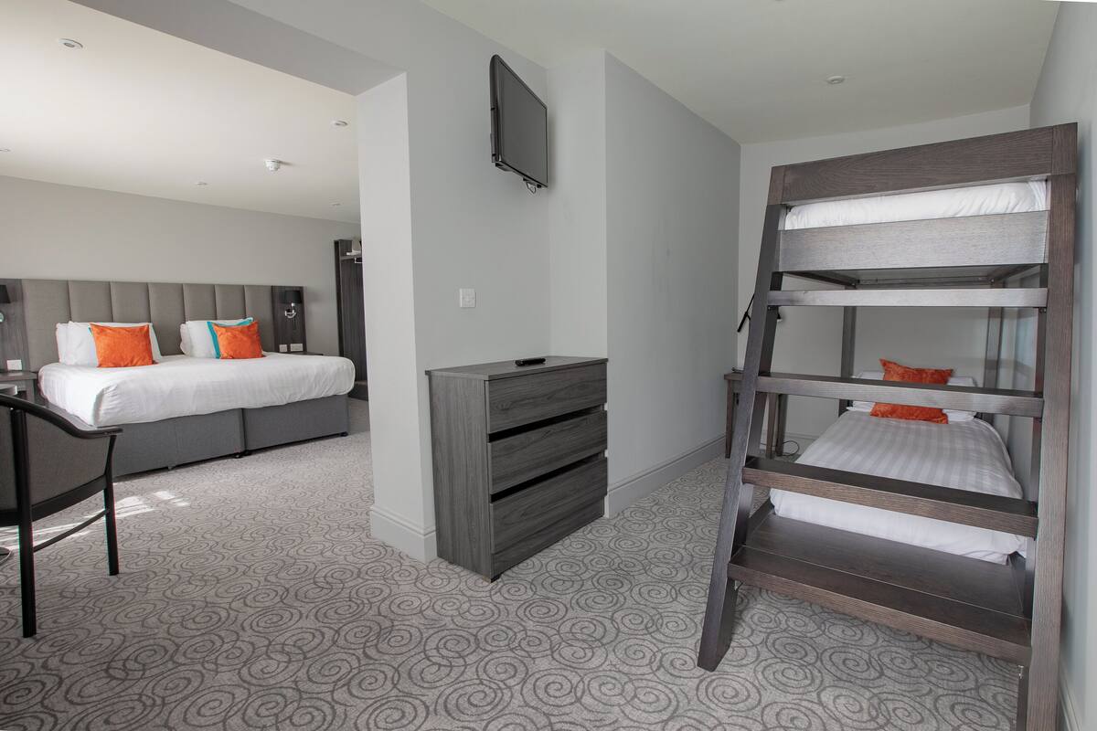 A hotel room with a bunk bed, a desk, and a dresser.