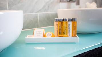 A bathroom with a white sink, a blue countertop, and a shelf with bath products including a cleansing bar and shampoo.