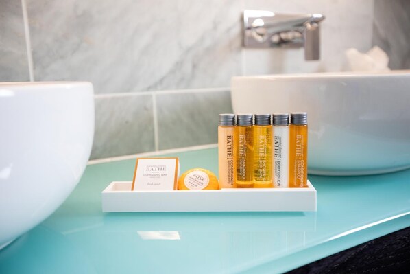 Un baño con un lavabo blanco, encimera azul y un estante con productos de baño, incluyendo una pastilla limpiadora y champú.
