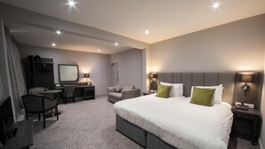 Une chambre d’hôtel avec un grand lit, un bureau, une chaise, une télévision et une armoire.