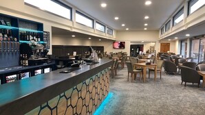 Un espace bar moderne doté d’un comptoir, de sièges et d’un écran de télévision.