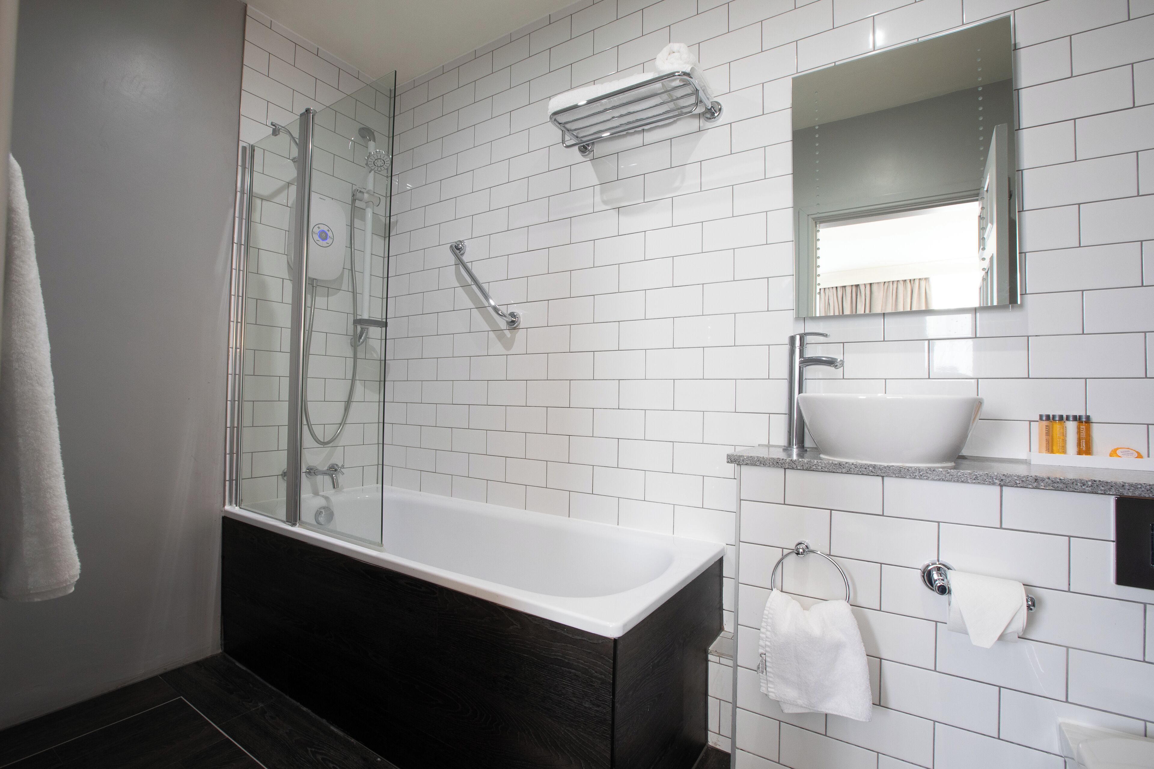 A modern bathroom with a glass-enclosed shower, a freestanding bathtub, a vanity with a sink, and a mirror above the sink.