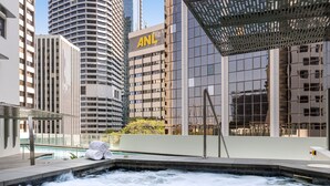 A hot tub with a view of tall buildings, including one with the 'ANL' logo. - Oaks Brisbane Aurora Suites (Brisbane)