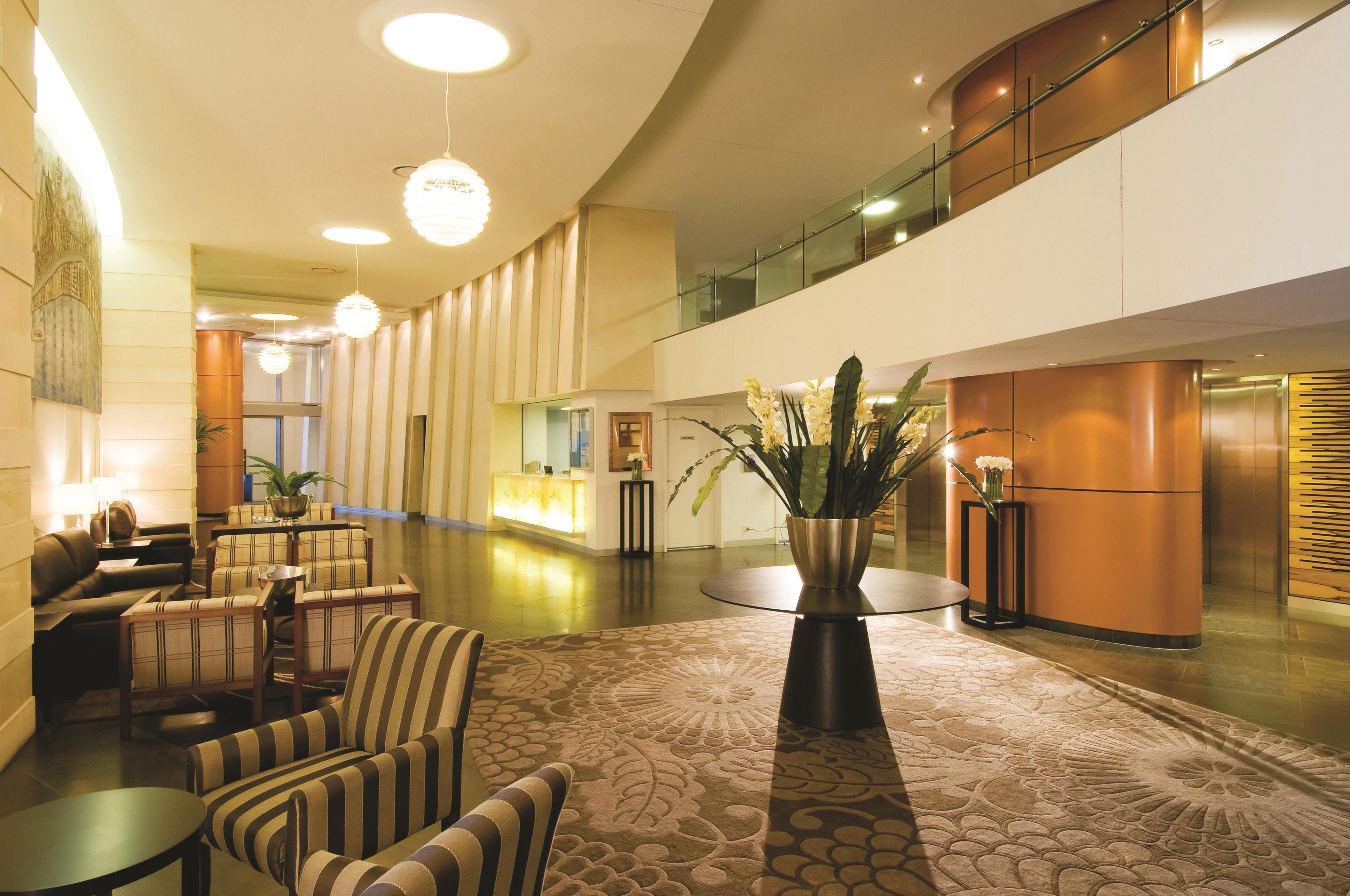 Hall d'hotel con reception, area salotto e composizione floreale decorativa.