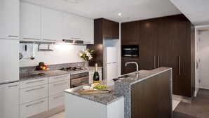 Una cocina moderna con armarios blancos y de madera oscura, una encimera de granito y una isla integrada con fregadero.