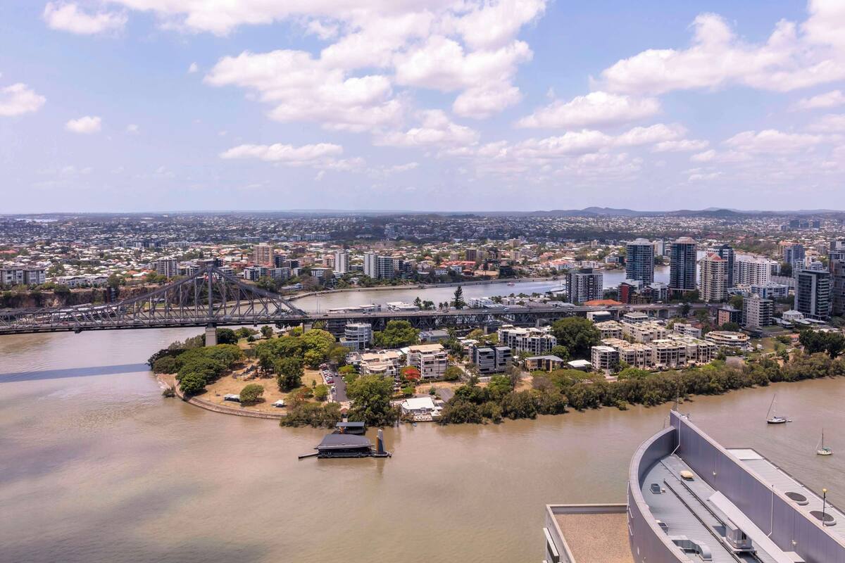 A cityscape with a river, a bridge, and a waterfront area with buildings and greenery.