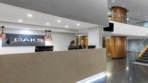 Un área de recepción moderna con un mostrador, una pantalla digital y un cartel de OAKS Hotels & Resorts.