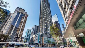 A modern urban street with high-rise buildings, including a prominent curved skyscraper. - Oaks Brisbane Aurora Suites (Brisbane)