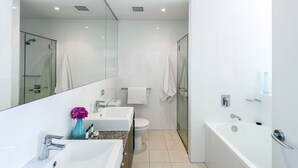 Un baño moderno con cabina de ducha de vidrio, lavamanos blanco, inodoro y bañera.