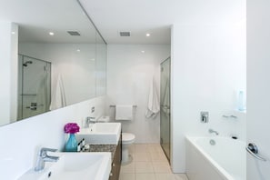 Een moderne badkamer met een douchecabine van glas, een witte wastafel, toilet en ligbad.