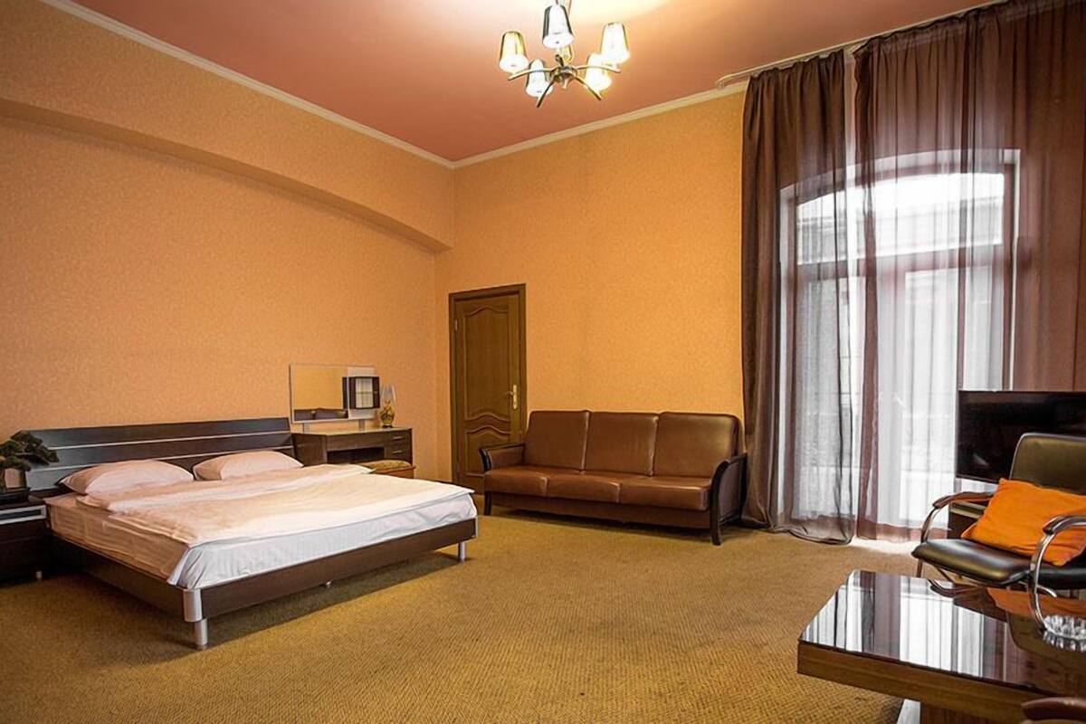 A hotel room with a bed, a sofa, a TV, and a coffee table.