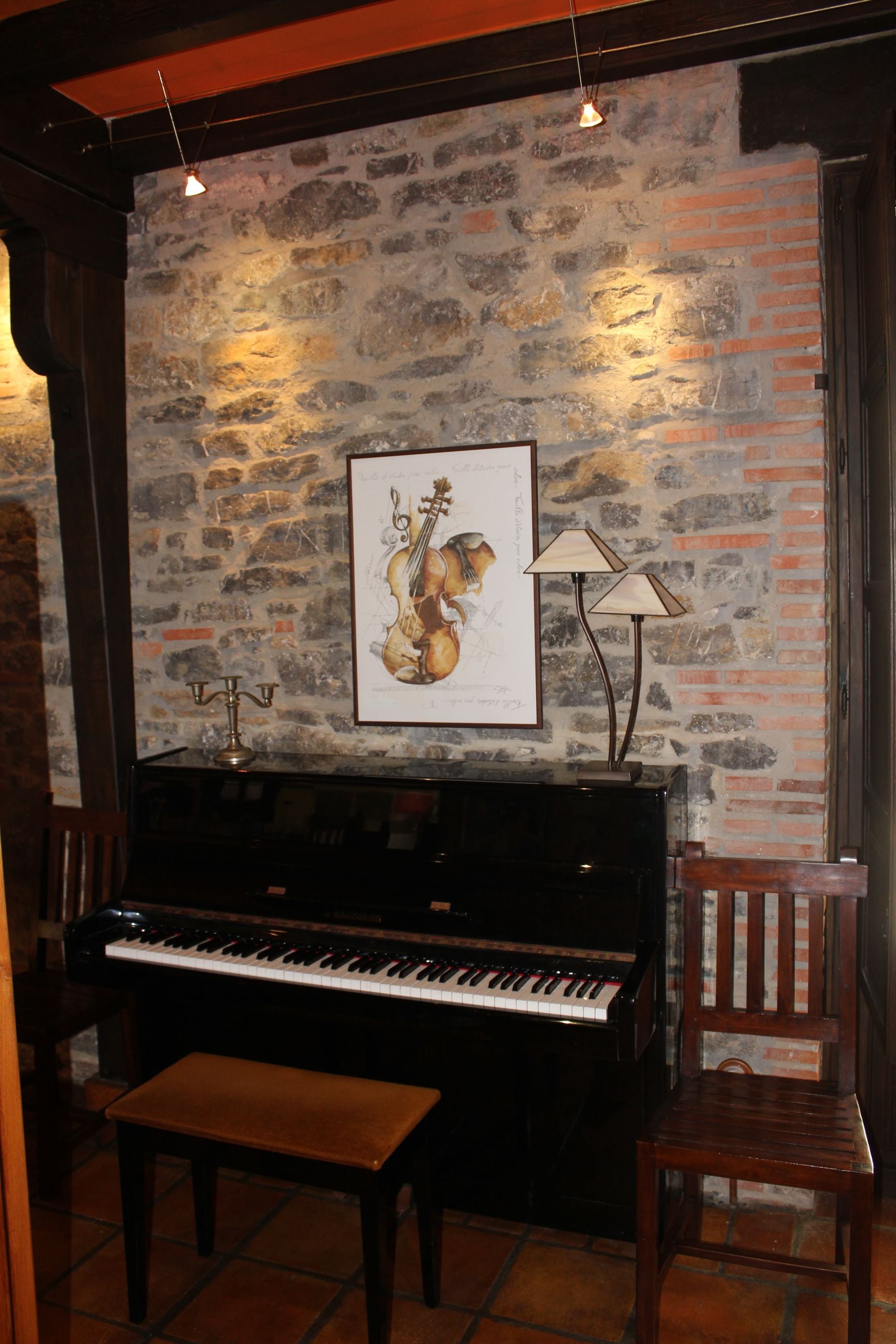 Un piano con un banco delante, un cuadro en la pared y una lámpara.