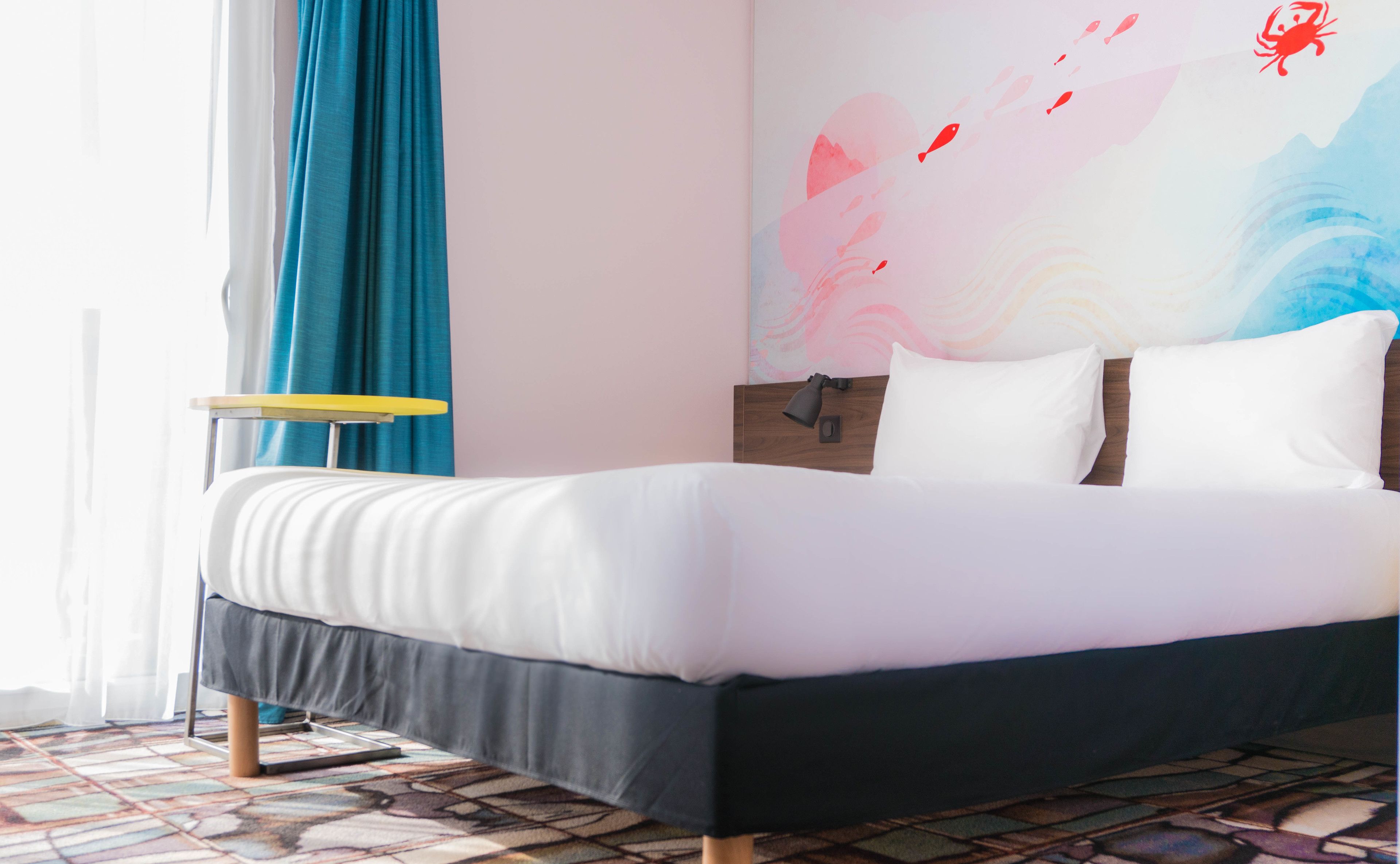 A modern bedroom with a bed, a bedside table, and a wall with abstract art.