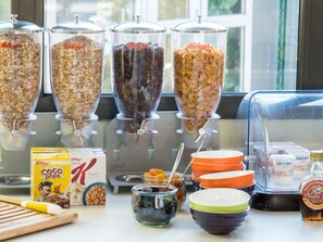 A breakfast bar with various food items and containers, including cereal and condiments.