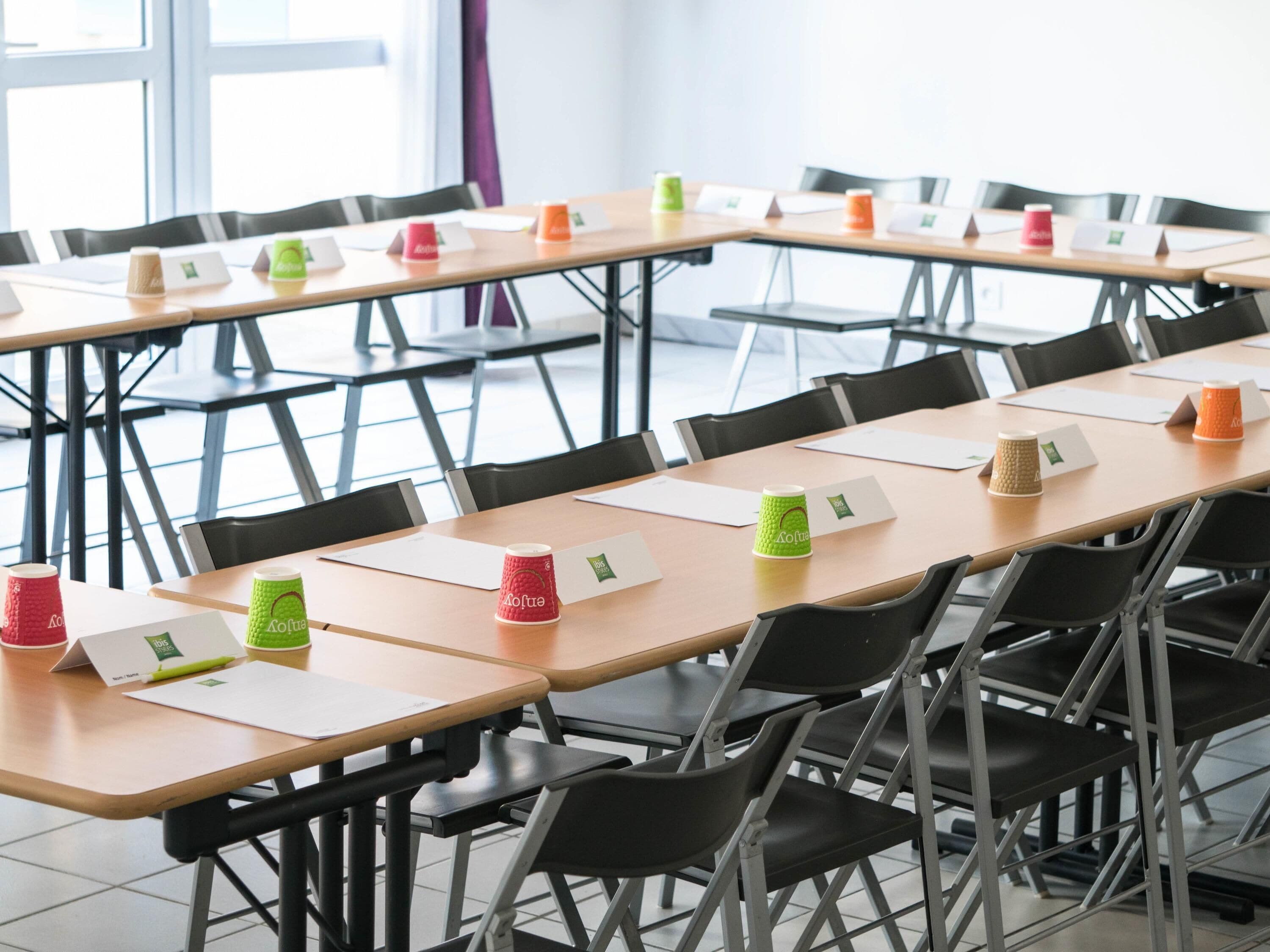 A conference room with tables, chairs, and coffee cups.