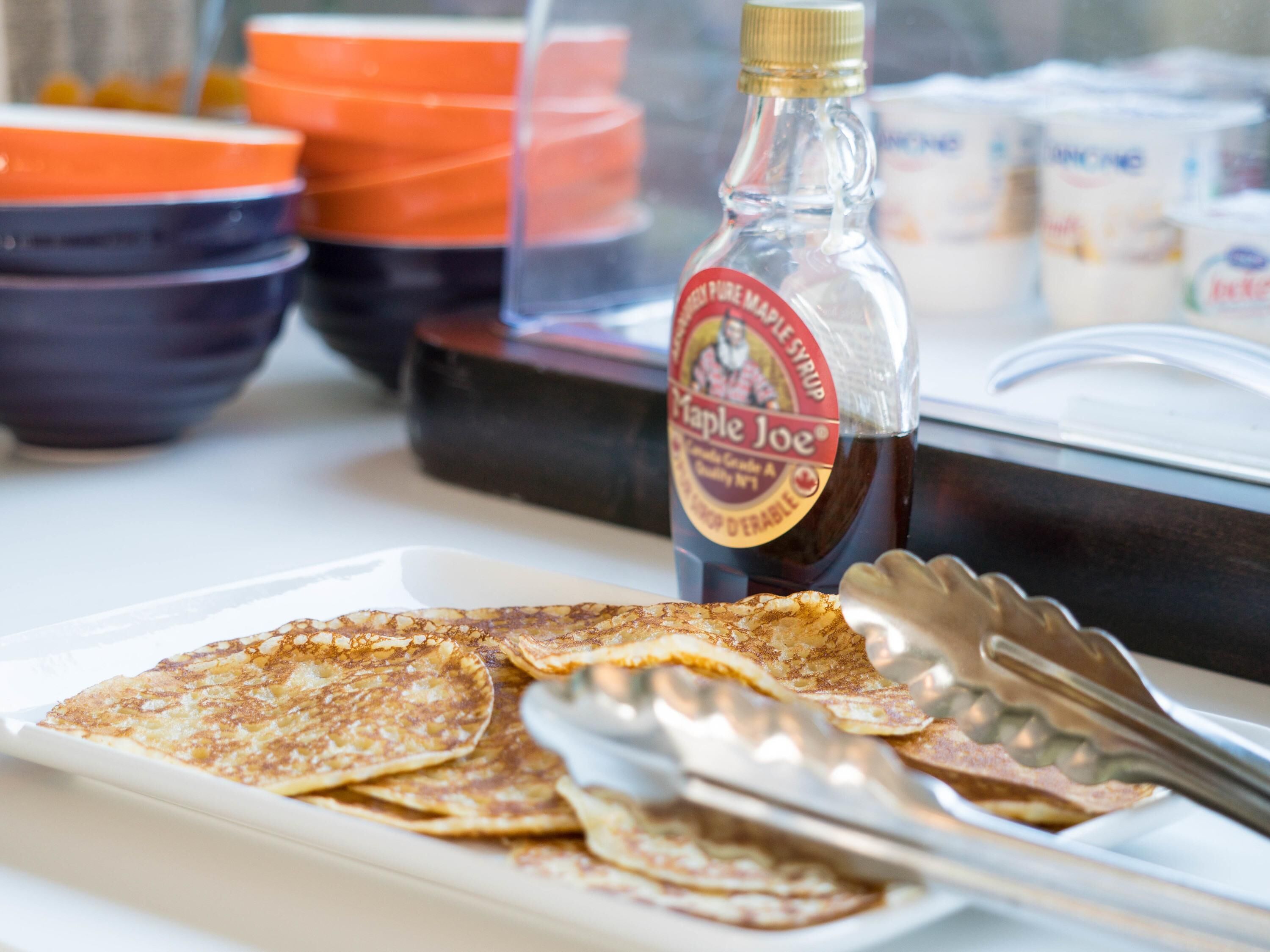 A breakfast setting with pancakes, syrup, and utensils.