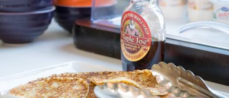 A breakfast setting with pancakes, syrup, and utensils.