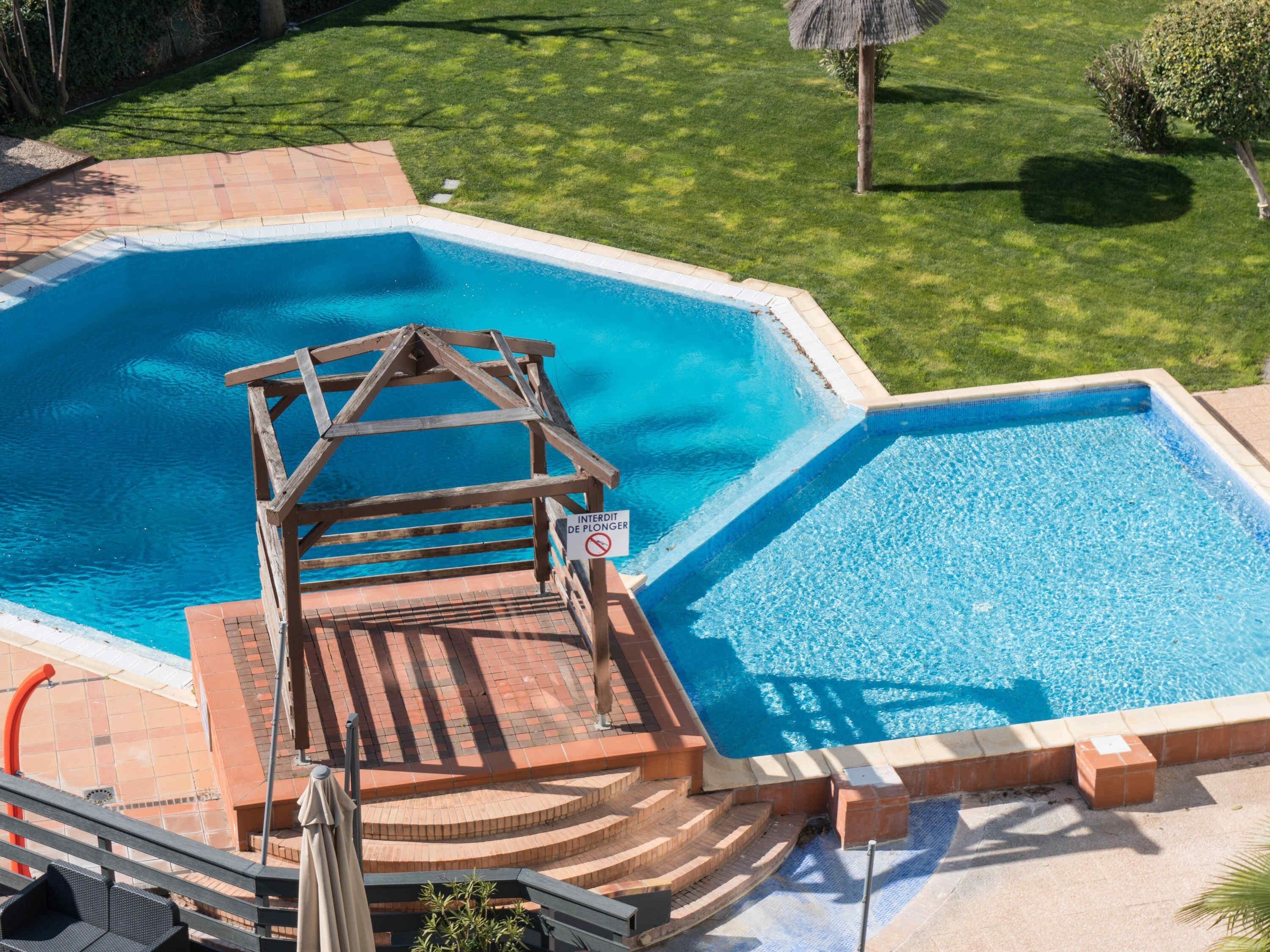 Een seizoensgebonden buitenzwembad en ligstoelen