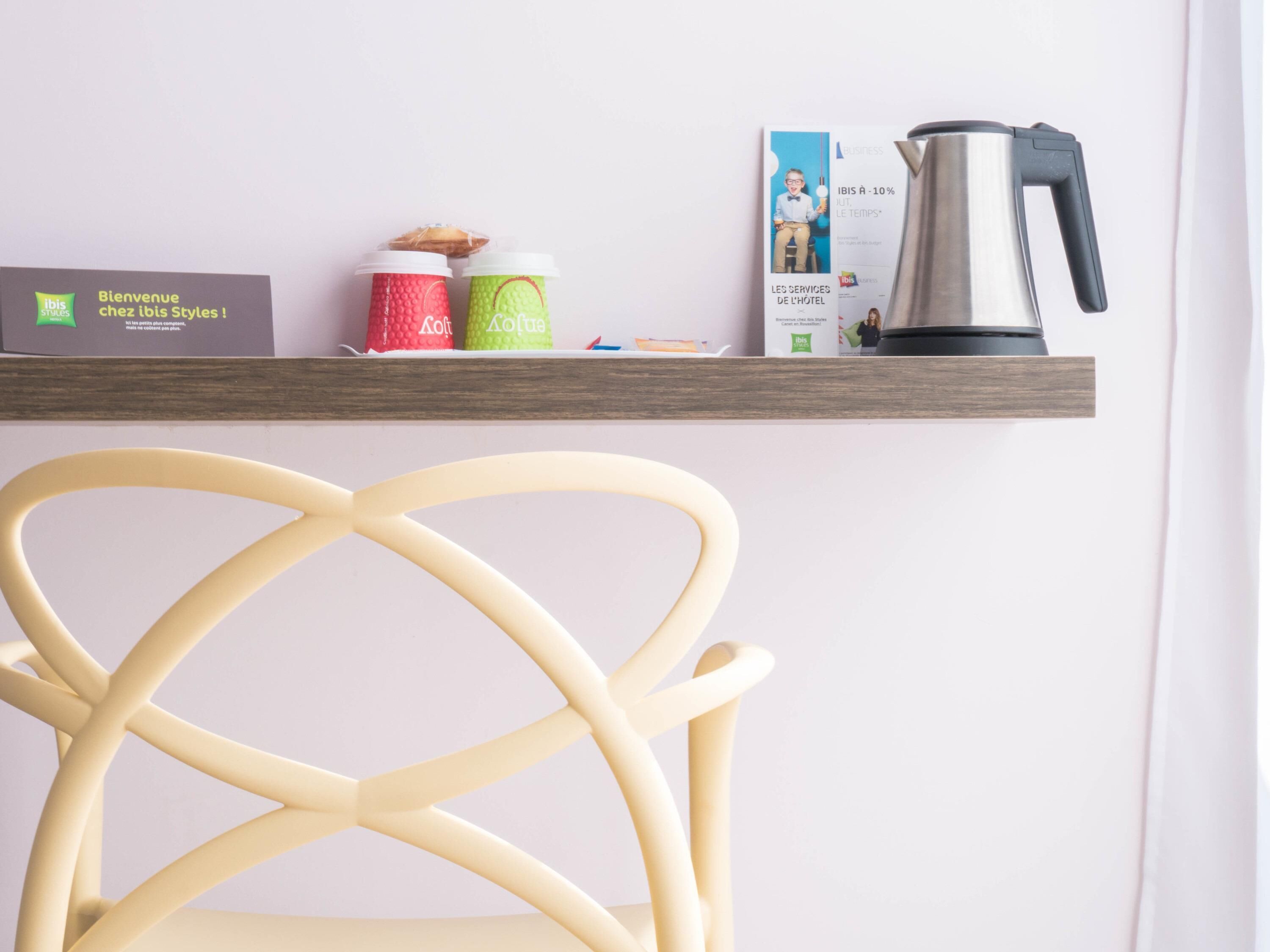 A shelf with a coffee maker, two cups, a box, and a chair.