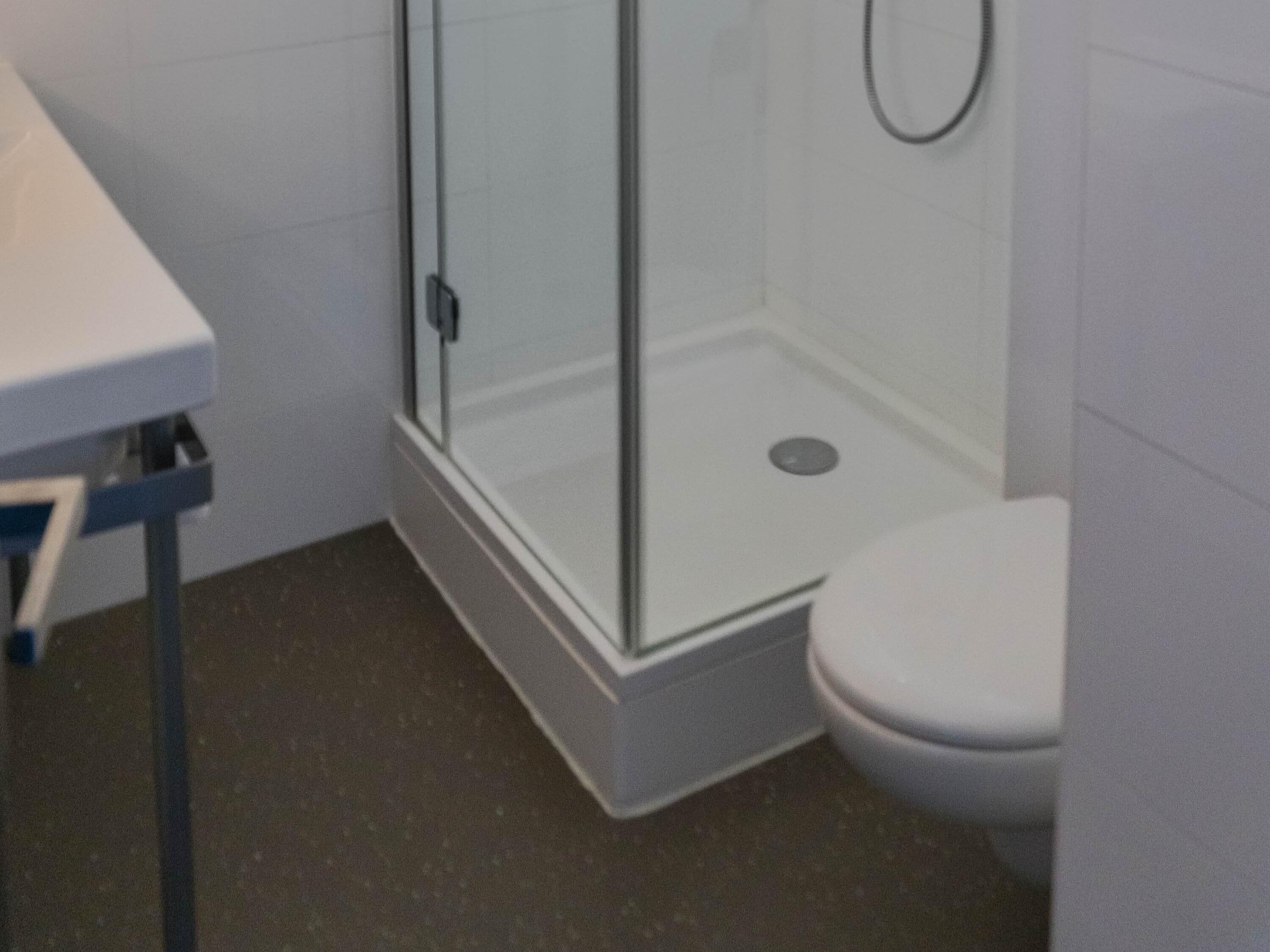 Un bagno con cabina doccia in vetro, un WC bianco e un lavandino con piano di appoggio blu.