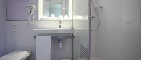 Un baño con inodoro, lavabo, espejo y ducha.
