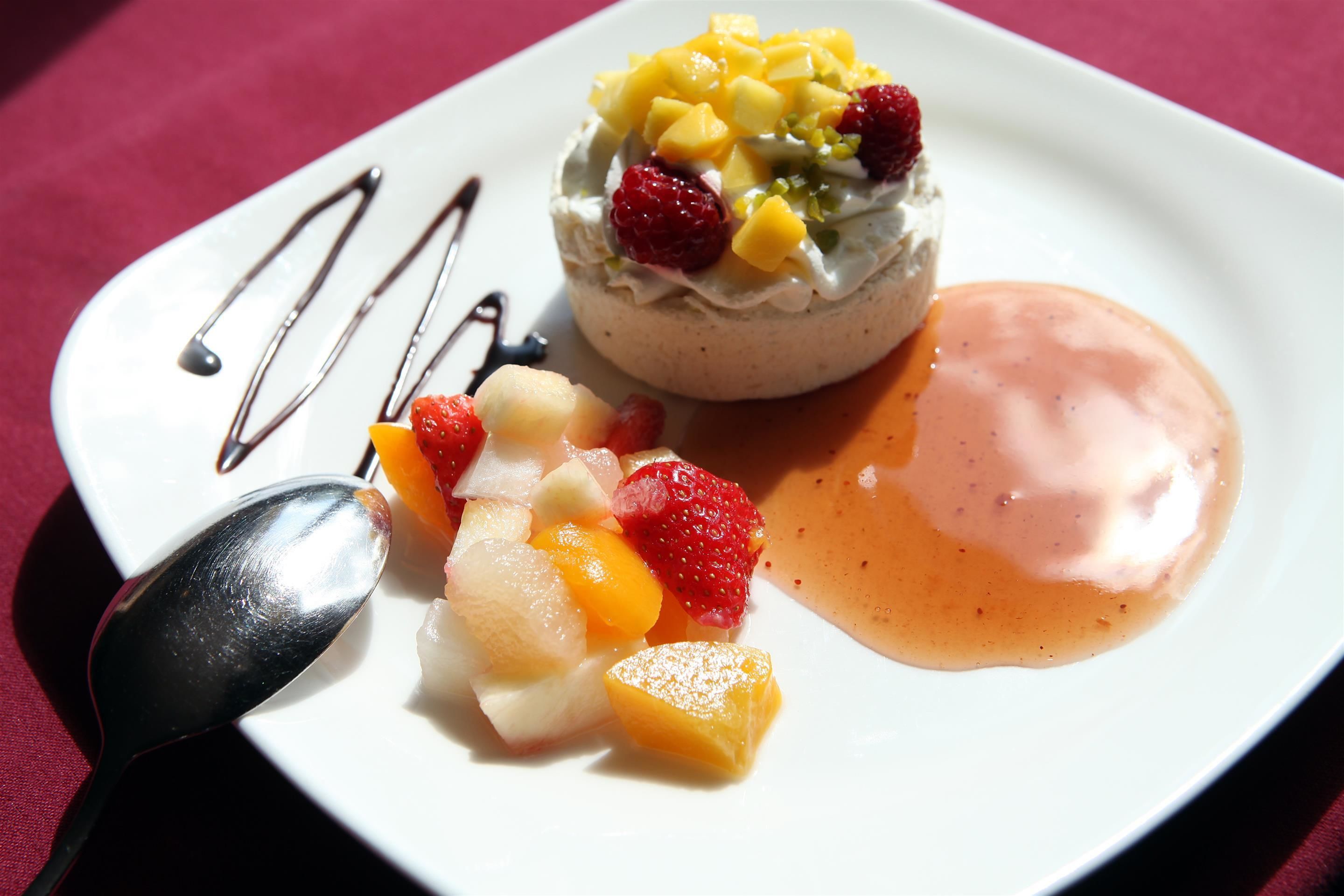A dessert plate with a meringue, fruit, and sauce.