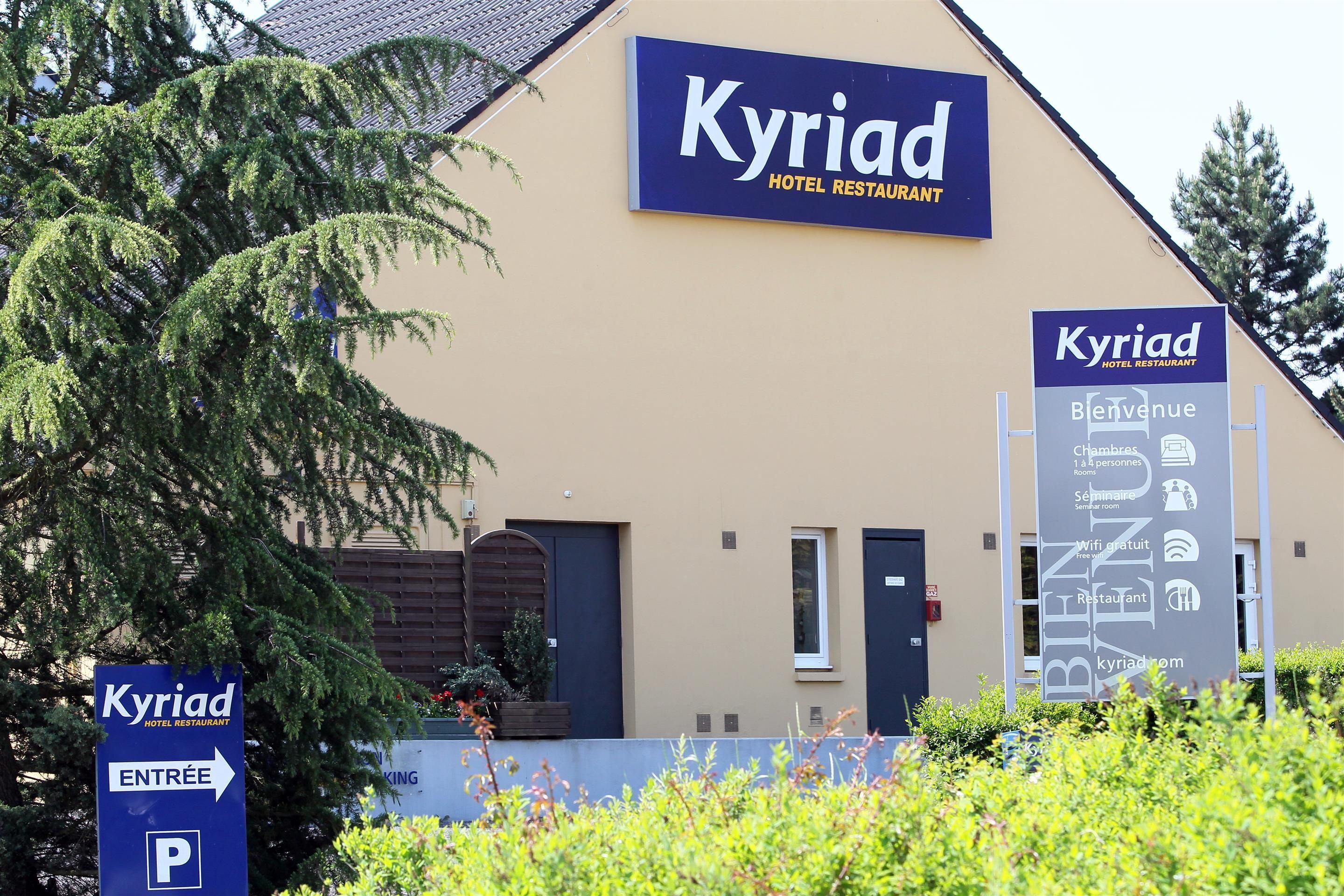 A hotel named Kyriad with a sign indicating the entrance and parking.