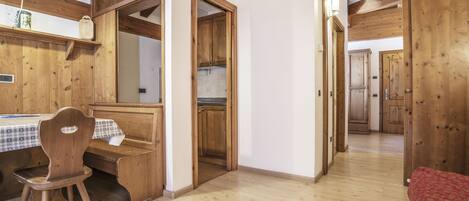 Un interior de madera con una mesa y sillas de comedor, una zona de cocina y un pasillo que conduce a otra habitación.