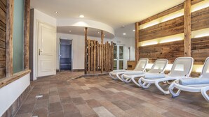 A spa area with a row of white lounge chairs, a wooden wall, and a tiled floor. - Sporting Clubresidence (Primiero San Martino di Castrozza)